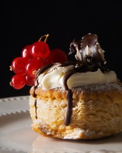 Postre de hojaldre, crema y chocolate con guindas.